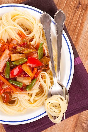simsearch:656-02702879,k - Culinary pasta eating. Pasta with tomato vegetable sauce on plate with cutlery on wooden background, top view. Photographie de stock - Aubaine LD & Abonnement, Code: 400-07681109