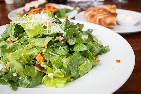 salada caesar - Closed up caesar salad served on wooden table, stock photo Foto de stock - Royalty-Free Super Valor e Assinatura, Número: 400-07681652