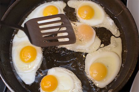 simsearch:700-03451646,k - Cooking fried eggs with a close up view from above of a batch of partially cooked fried eggs sizzling in a frying pan over the heat Photographie de stock - Aubaine LD & Abonnement, Code: 400-07682401