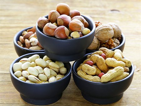 simsearch:400-07310170,k - different kinds of nuts (almonds, walnuts, hazelnuts, peanuts) in a bowl on a wooden table Fotografie stock - Microstock e Abbonamento, Codice: 400-07714060