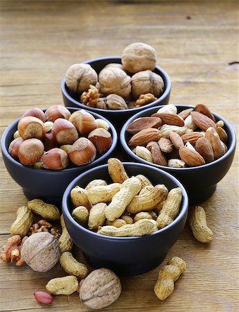 simsearch:400-07310170,k - different kinds of nuts (almonds, walnuts, hazelnuts, peanuts) in a bowl on a wooden table Fotografie stock - Microstock e Abbonamento, Codice: 400-07715085