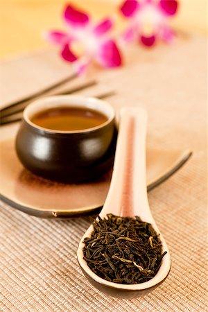 simsearch:400-05153477,k - Tea leaves o a tea spoon, cup of black tea, insence sticks and flowers in background Photographie de stock - Aubaine LD & Abonnement, Code: 400-07715731