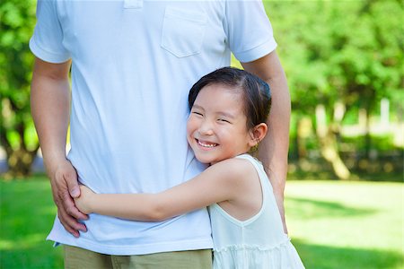 family relaxing with kids in the sun - smiling little girl hug father waist in the park Photographie de stock - Aubaine LD & Abonnement, Code: 400-07715953