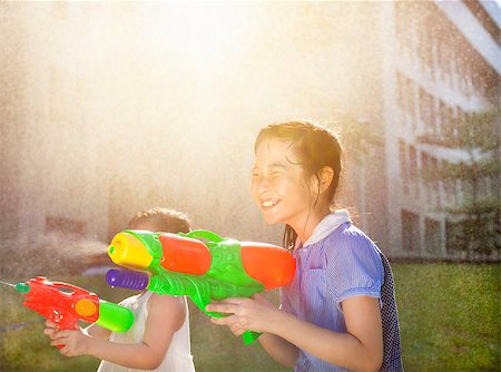simsearch:400-08320108,k - Cheerful girls playing water guns in the park Foto de stock - Royalty-Free Super Valor e Assinatura, Número: 400-07715962