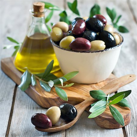 simsearch:400-07219392,k - Mixed marinated olives (green, black and purple) in ceramic bowl and wooden spoon with bottle of olive oil. Selective focus. Stock Photo - Budget Royalty-Free & Subscription, Code: 400-07716741