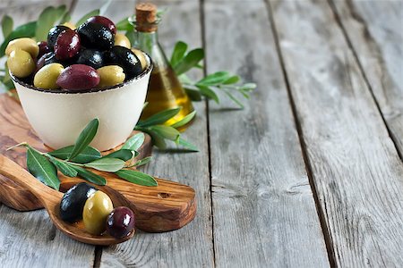 simsearch:400-07219392,k - Mixed marinated olives (green, black and purple) in ceramic bowl and wooden spoon with bottle of olive oil. Selective focus. Copy space background Stock Photo - Budget Royalty-Free & Subscription, Code: 400-07716742
