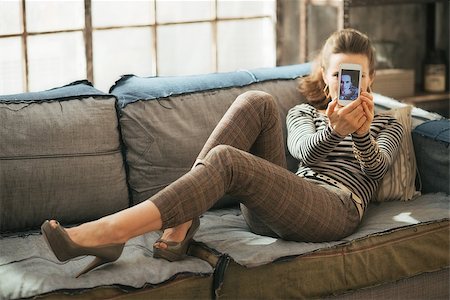 simsearch:400-08054469,k - Young woman taking self photo in loft apartment while laying on couch Stock Photo - Budget Royalty-Free & Subscription, Code: 400-07718485