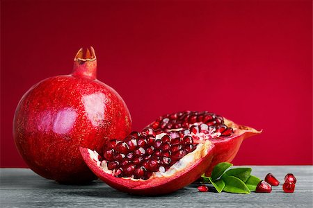 simsearch:400-06457388,k - Juicy pomegranate fruit with leaves  on a red background Photographie de stock - Aubaine LD & Abonnement, Code: 400-07718792