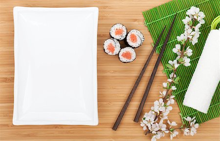 simsearch:400-07719212,k - Sushi maki with salmon and sakura branch over bamboo table and empty plate for copy space Fotografie stock - Microstock e Abbonamento, Codice: 400-07719213