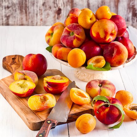simsearch:400-07667203,k - Ripe apricots, nectarines and saturn peaches on ceramic holder and olive wood desk with knife. Selective focus. Stock Photo - Budget Royalty-Free & Subscription, Code: 400-07713491