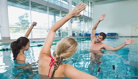 simsearch:400-07724709,k - Fitness class doing aqua aerobics on exercise bikes in swimming pool at the leisure centre Stock Photo - Budget Royalty-Free & Subscription, Code: 400-07724716