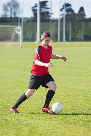 Football player in red playing on pitch on a clear day Stock Photo - Budget Royalty-Free & Subscription, Code: 400-07724906