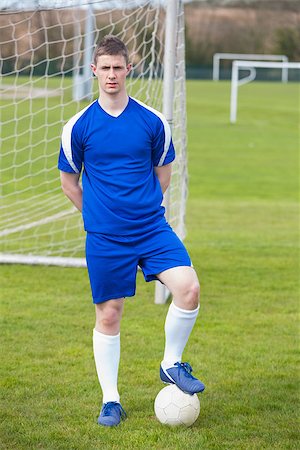 Football player in blue posing with the ball on pitch on a clear day Stock Photo - Budget Royalty-Free & Subscription, Code: 400-07724934