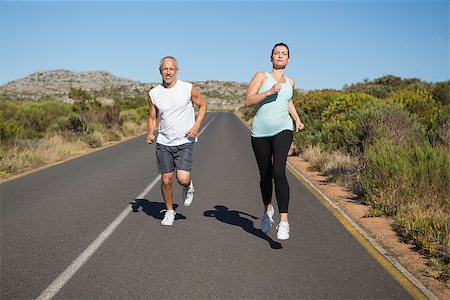 simsearch:400-08017381,k - Fit couple running on the open road together on a sunny day Photographie de stock - Aubaine LD & Abonnement, Code: 400-07724975