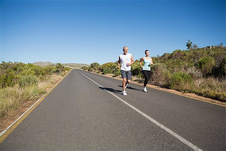 simsearch:400-08017381,k - Fit couple running on the open road together on a sunny day Photographie de stock - Aubaine LD & Abonnement, Code: 400-07724977