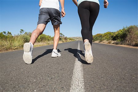 simsearch:400-08017381,k - Fit couple running on the open road together on a sunny day Photographie de stock - Aubaine LD & Abonnement, Code: 400-07724981