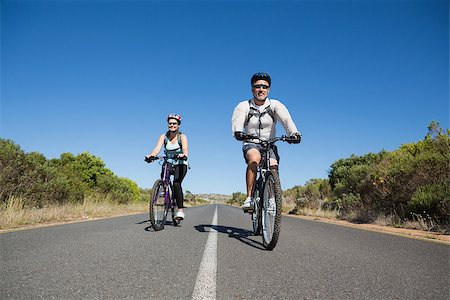 rodovia 40 - Fit smiling couple going for a bike ride in the countryside on a sunny day Foto de stock - Royalty-Free Super Valor e Assinatura, Número: 400-07725002