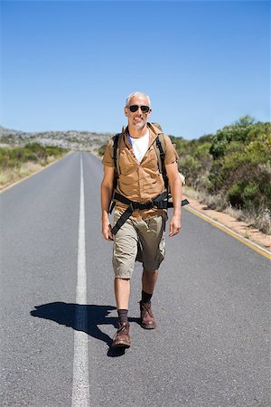 rodovia 40 - Handsome hiker walking on road and smiling at camera on a sunny day Foto de stock - Royalty-Free Super Valor e Assinatura, Número: 400-07725063