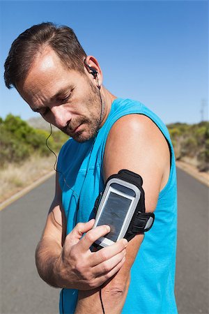 simsearch:400-07725266,k - Athletic man changing the music on a run on a sunny day Photographie de stock - Aubaine LD & Abonnement, Code: 400-07725267
