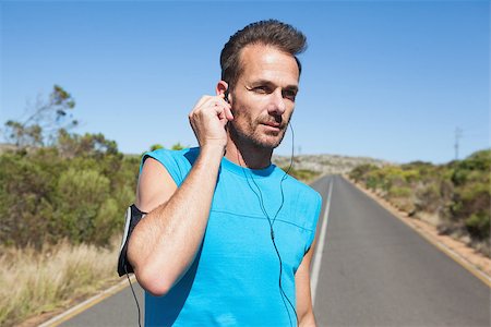 simsearch:400-07725266,k - Athletic man adjusting his earphones on a run on a sunny day Photographie de stock - Aubaine LD & Abonnement, Code: 400-07725268