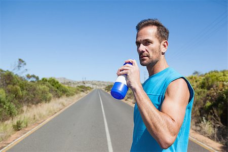 simsearch:400-08017390,k - Athletic man on open road taking a drink on a sunny day Photographie de stock - Aubaine LD & Abonnement, Code: 400-07725276