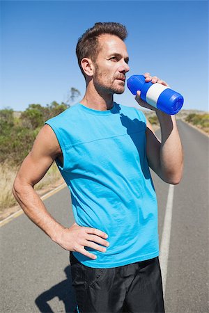 simsearch:400-07725266,k - Athletic man on open road taking a drink on a sunny day Photographie de stock - Aubaine LD & Abonnement, Code: 400-07725278