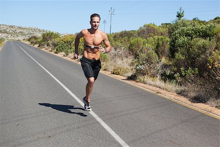 simsearch:400-07725266,k - Athletic man jogging on open road with monitor around chest on a sunny day Photographie de stock - Aubaine LD & Abonnement, Code: 400-07725271