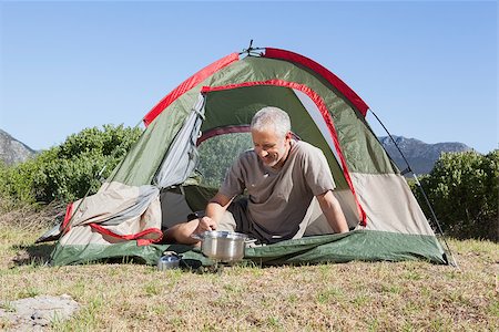 Happy camper cooking on camping stove outside his tent on a sunny day Stock Photo - Budget Royalty-Free & Subscription, Code: 400-07725364