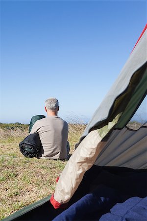 sleep in camper - Happy camper sitting outside his tent holding sleeping bag on a sunny day Stock Photo - Budget Royalty-Free & Subscription, Code: 400-07725377