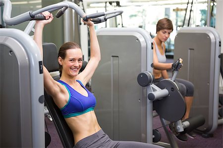 simsearch:400-07725772,k - Healthy brunette using weights machine for arms at the gym Photographie de stock - Aubaine LD & Abonnement, Code: 400-07725671