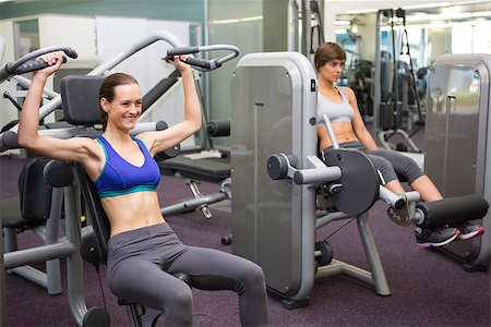 simsearch:400-07725772,k - Healthy brunette using weights machine for arms at the gym Photographie de stock - Aubaine LD & Abonnement, Code: 400-07725672