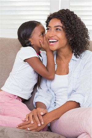 Pretty mother sitting on the couch with her daughter whispering a secret at home in the living room Stock Photo - Budget Royalty-Free & Subscription, Code: 400-07726167
