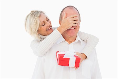 simsearch:400-07726694,k - Older woman covering her partners eye while holding present on white background Foto de stock - Royalty-Free Super Valor e Assinatura, Número: 400-07726380