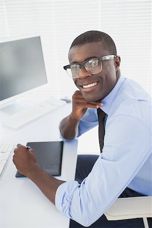 simsearch:400-07926810,k - Hipster businessman smiling at camera at his desk in his office Fotografie stock - Microstock e Abbonamento, Codice: 400-07727343