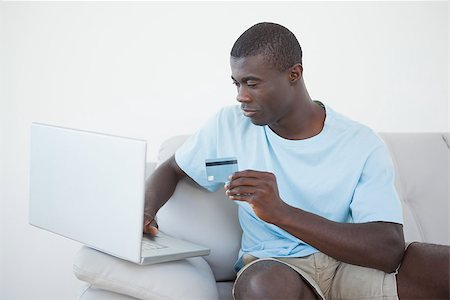 simsearch:400-07474252,k - Casual man sitting on sofa using laptop to shop online at home in the living room Stock Photo - Budget Royalty-Free & Subscription, Code: 400-07727542