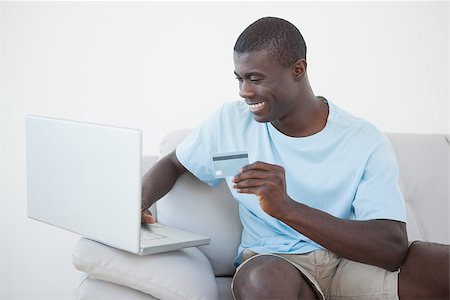 simsearch:400-07474252,k - Casual man sitting on sofa using laptop to shop online at home in the living room Stock Photo - Budget Royalty-Free & Subscription, Code: 400-07727543