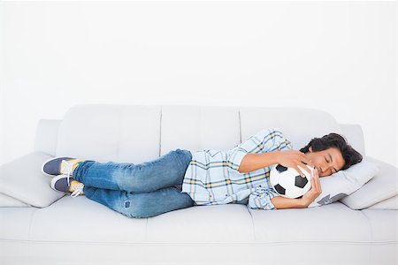 football fan on couch - Football fan sleeping on couch hugging ball at home in the living room Stock Photo - Budget Royalty-Free & Subscription, Code: 400-07728032