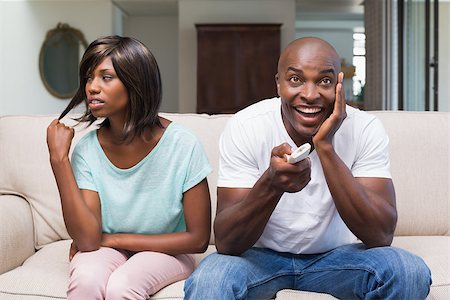 Bored woman sitting next to her boyfriend watching tv at home in the living room Stock Photo - Budget Royalty-Free & Subscription, Code: 400-07722039