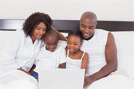 Happy family using laptop together in bed at home in the bedroom Stock Photo - Budget Royalty-Free & Subscription, Code: 400-07722177