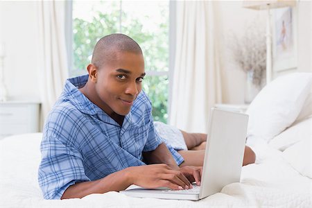 Happy man using laptop on bed at home in the bedroom Stock Photo - Budget Royalty-Free & Subscription, Code: 400-07722443