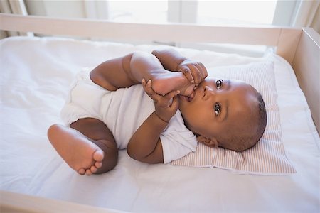 Adorable baby boy lying in his crib chewing foot at home in the bedroom Stock Photo - Budget Royalty-Free & Subscription, Code: 400-07722550