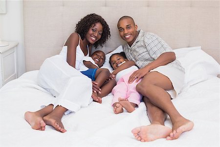 simsearch:642-01735522,k - Happy family smiling at camera together on bed at home in the bedroom Foto de stock - Super Valor sin royalties y Suscripción, Código: 400-07722596