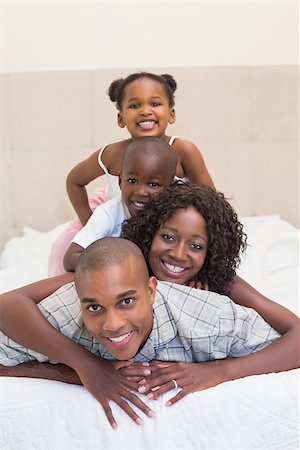 simsearch:642-01735522,k - Happy family smiling at camera together on bed at home in the bedroom Foto de stock - Super Valor sin royalties y Suscripción, Código: 400-07722597