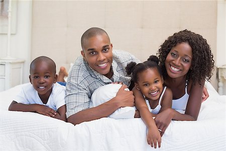 simsearch:642-01735522,k - Happy family smiling at camera together on bed at home in the bedroom Foto de stock - Super Valor sin royalties y Suscripción, Código: 400-07722599