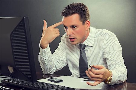 shooting the head with the hand - Young shocked desperate businessman in white shirt and tie pointing his finger to his head in a shoot himself gesture after receiving bankruptcy news in front of his computer at work. Stock Photo - Budget Royalty-Free & Subscription, Code: 400-07745216