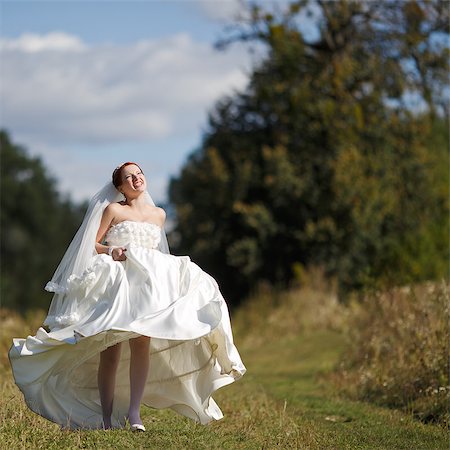 Happy caucasian bride walking field, wearing gorgeous dress. Photographie de stock - Aubaine LD & Abonnement, Code: 400-07745414