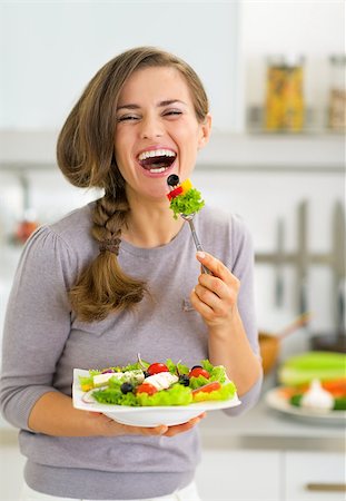 person eating greek salad - Happy young woman eating greek salad in kitchen Stock Photo - Budget Royalty-Free & Subscription, Code: 400-07748427