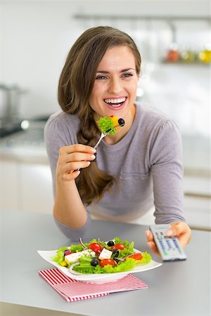 person eating greek salad - Young woman eating greek salad and watching tv Stock Photo - Budget Royalty-Free & Subscription, Code: 400-07748428