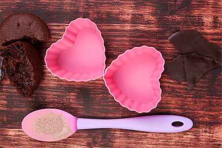 Baking delicious muffins. Chocolate baking mixture, fresh muffins and pink heart shaped baking forms on brown wooden background, top view. Stock Photo - Budget Royalty-Free & Subscription, Code: 400-07749461
