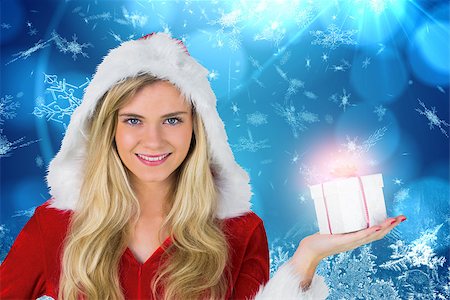 simsearch:400-07834588,k - Pretty girl in santa outfit holding gift against blue snow flake pattern design Fotografie stock - Microstock e Abbonamento, Codice: 400-07755432